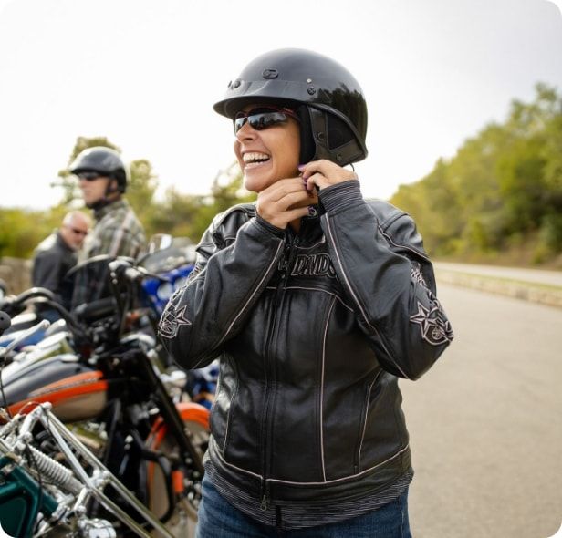 A woman fastening her helmet before riding a motorcycle. 