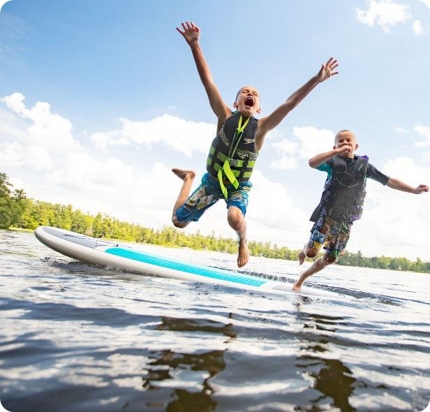 Two boys excitedly jumping into the lake.