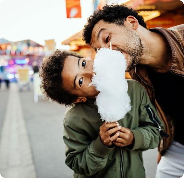 Father and son share cotton candy at the fair. 