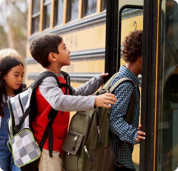 Three children climbing aboard a school bus. 