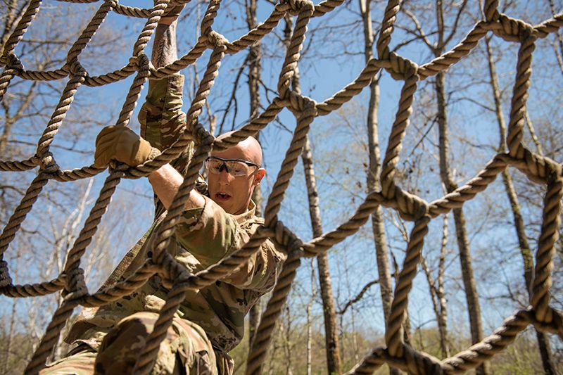 A soldier climbing through a rope net. 